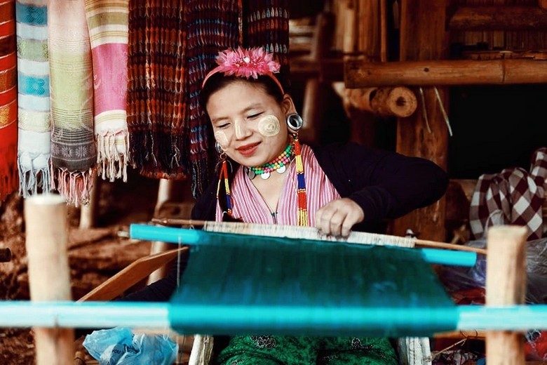 Phụ nữ Kayan ngồi dệt vải bên khung cửi trong làng